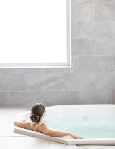 Kobieta zażywająca kąpieli z hydromasażem w narożnym jacuzzi przy dużym oknie, jesienny relaks w spa Hotelu Jurajski Kryształ