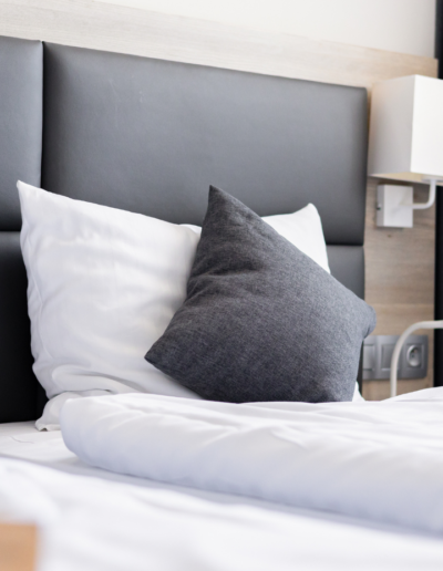 Zbliżenie na miękkie poduszki i wygodne łóżko z ciemnoszarym tapicerowanym wezgłowiem w pokoju Hotelu Jurajski Kryształ