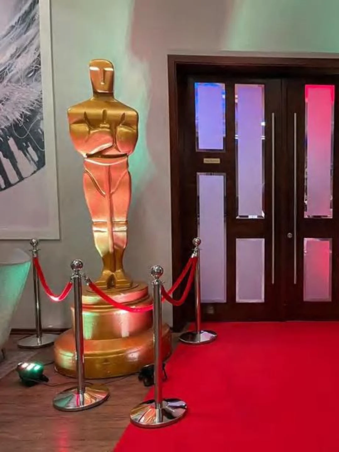 Złota statuetka Oscara obok czerwonego dywanu i wejścia do sali