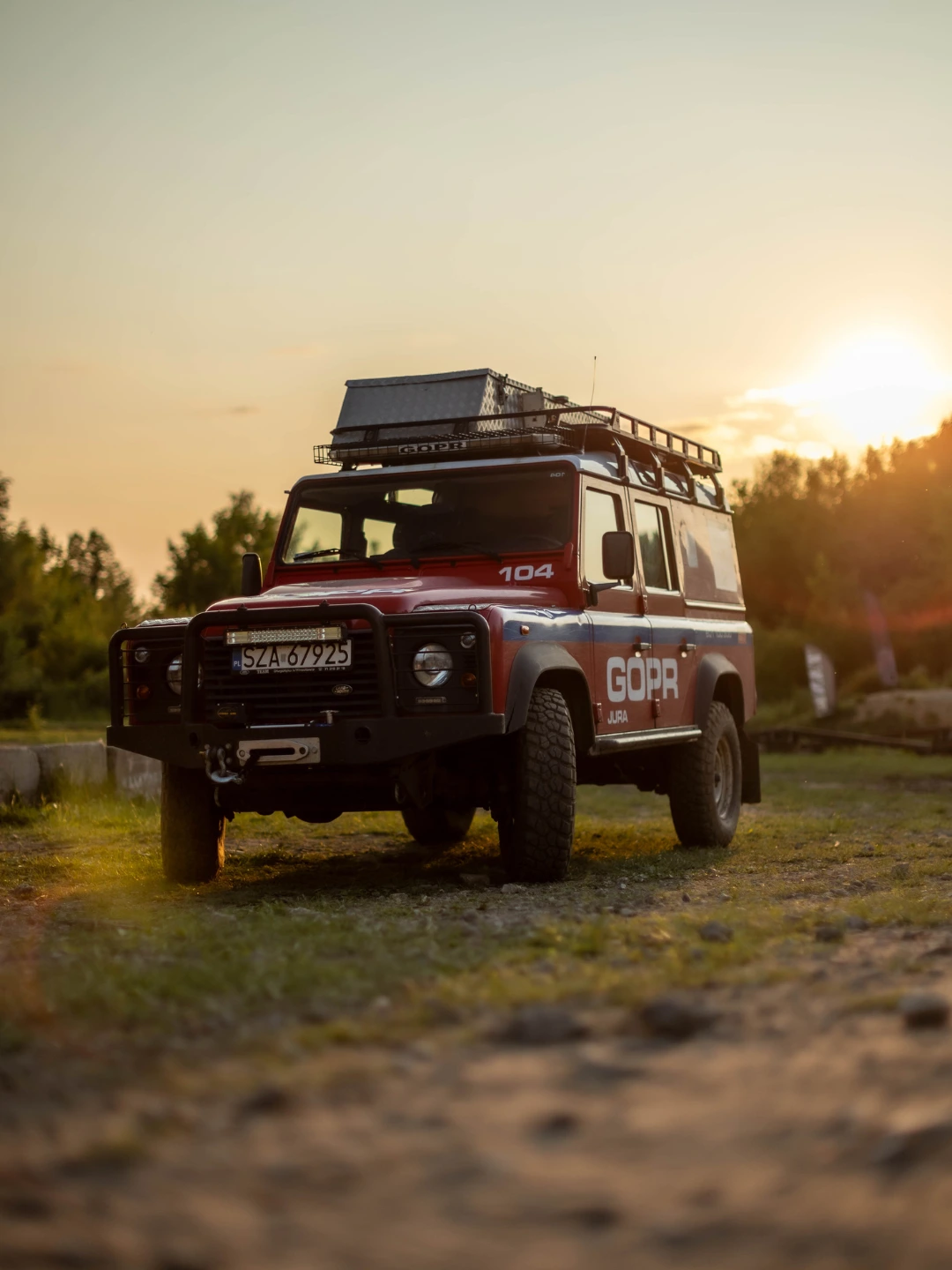Czerwony ratowniczy Land Rover GOPR zaparkowany na plenerowym torze o zachodzie słońca